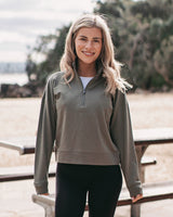 woman in a green 1/2 zip sweatshirt standing in front of a picnic table