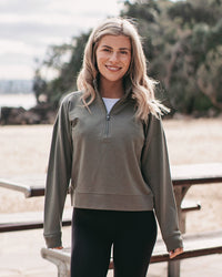 woman in a green 1/2 zip sweatshirt standing in front of a picnic table