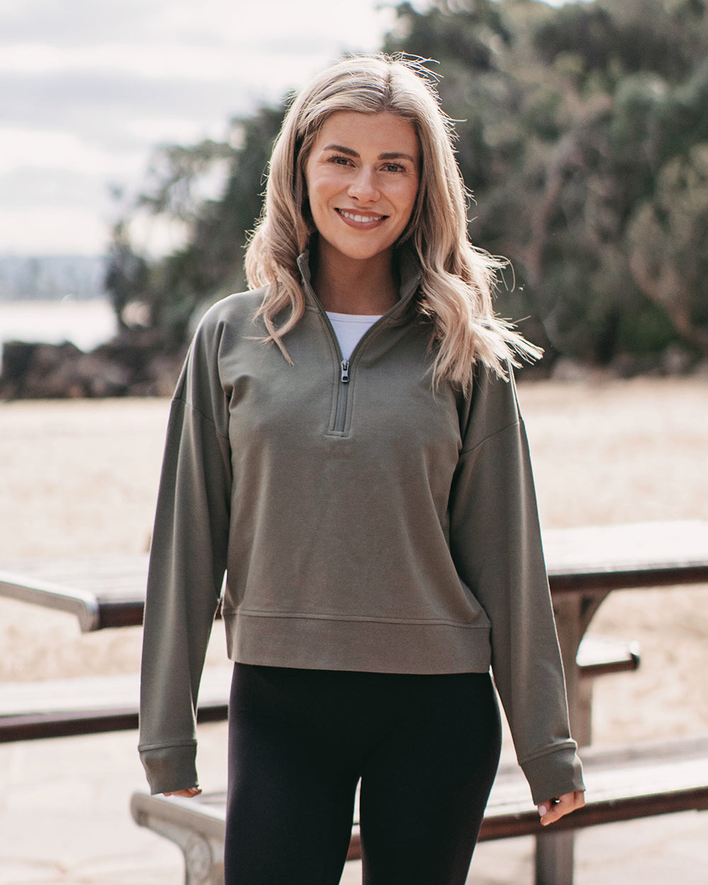 woman in a green 1/2 zip sweatshirt standing in front of a picnic table